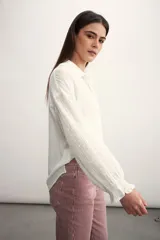 Camisa blanca de mangas largas con detalles bordados y cuello clásico.