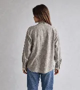Camisa gris de algodón con textura sutil, corte relajado y mangas amplias. Cuenta con cuello mao con lazo largo para anudar, y detalles de puntilla blanca a contratono en la parte delantera y en los puños.