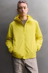 Chaqueta acolchada Zara Athleticz de color amarillo, confeccionada en tejido técnico y ligero. Cuenta con cuello subido y capucha, manga larga con puños elásticos, bolsillos frontales con cierre de cremallera oculta y cierre frontal con cremallera.