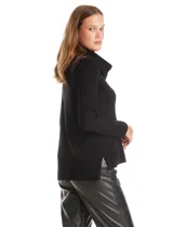 Buzo de punto color beige con cuello volcado amplio, mangas largas acanaladas y torso liso. Presenta una costura central vertical, ruedo con tajos laterales y largo asimétrico, siendo más largo en la parte posterior.