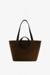 Bolso tipo tote amplio de ante marrón, con doble asa larga negra para el hombro y detalle gráfico frontal en forma de C con asas cortas integradas.