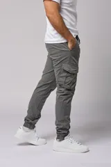 Pantalón cargo color beige de gabardina, con corte ajustado, bolsillos laterales con fuelle y puños elásticos en los tobillos.