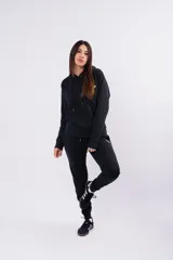 Conjunto deportivo compuesto por un buzo con capucha y un pantalón de jogging, ambos en color negro. El buzo presenta un diseño liso con cordones ajustables en la capucha, mientras que el pantalón cuenta con un pequeño logo bordado en la parte superior.