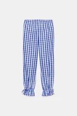 Pantalón de nylon con estampado de cuadros vichy azul y blanco. Presenta cintura elástica y bajo con volante fruncido y elástico.