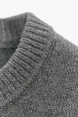 Chaleco de punto confeccionado en mezcla de lana color gris. Presenta cuello redondo, manga sisa con detalle de pliegues en los hombros y un bajo ancho en punto elástico que entalla la cintura.