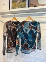 Remera de microtul con estampado abstracto en tonos azules, marrones y beige, de manga larga y cuello redondo.