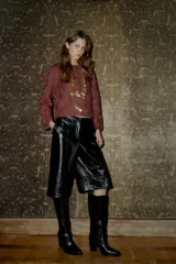 Bermuda negra de tiro alto con efecto piel, bolsillos delanteros y falsos bolsillos de vivo en la espalda. Cierre frontal con cremallera, botón interior y gancho.