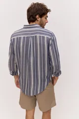 Camisa de manga larga de lino con diseño a rayas en tonos celestes y blancos, cuello camisero clásico y cierre frontal de botones.