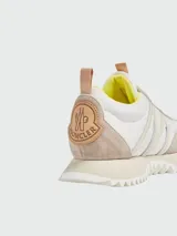 Zapatillas urbanas Moncler modelo Pacey, color blanco y beige, con detalles en amarillo y suela dentada. Presentan el logo de la marca en el lateral.