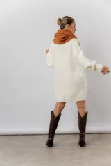 Buzo tipo sweater de punto color blanco, con diseño de trenzas verticales, cuello redondo, mangas largas y tajos laterales. Presenta un corte oversize y largo extendido.