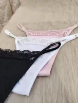 Pack de tres tangas de algodón en colores rosa, blanco y negro, con detalle de encaje en la parte superior y tiras regulables.