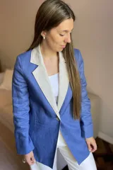 Blazer azul de lino con corte entallado, cuello y solapas combinadas en color gris, cierre con botón de nácar, bolsillos laterales y tajo en la espalda.