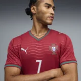 Camiseta de fútbol Puma de la selección de Portugal, modelo Home, color rojo con detalles en verde en el cuello y las mangas. Presenta un patrón de ondas sutil en la tela, el logo de Puma en blanco y el escudo de la Federación Portuguesa de Fútbol en el pecho.