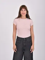 Remera de manga corta color rosado pálido, confeccionada en tejido acanalado, con cuello redondo.