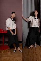 Falda midi de color negro con silueta amplia y caída suave. Presenta cintura elástica y bolsillos laterales integrados en el diseño.