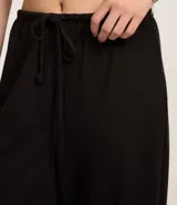 Pantalón flare negro con textura acanalada, cintura elástica con lazo y confeccionado con viscosa certificada.