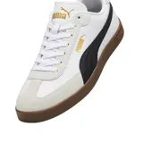 Championes Puma modelo Club Li Era, con diseño de perfil bajo en color negro, franja lateral blanca característica de la marca y suela de goma color caramelo. Presenta detalles en dorado en el logo lateral y la lengüeta.