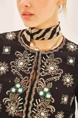 Saco corto de corte entallado con escote redondo, confeccionado en tejido negro con bordados artesanales de lentejuelas y pedrería en forma de estrellas y motivos florales en frente, espalda y mangas.