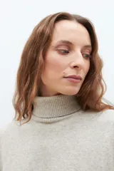 Sweater beige melange de cuello alto, tejido de punto liso y corte clásico.