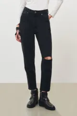 Jean de corte mom en color negro, con diseño de tiro alto, cinco bolsillos y detalle de rotura en la rodilla izquierda.