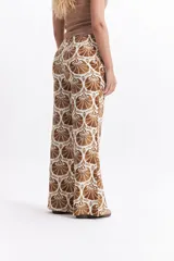 Pantalón wide leg estampado con diseño de conchas marinas en tonos verde oscuro y blanco. Presenta un calce relajado y cintura media.