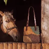 Cartera tipo tote de diseño patchwork, confeccionada en gamuza combinada en tonos tostado, marrón, bordó y verde. Cuenta con doble asa de hombro y detalles de cuero liso en los bordes.