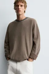 Jersey de manga larga, cuello redondo y calce relajado, color negro con efecto lavado y textura tejida.