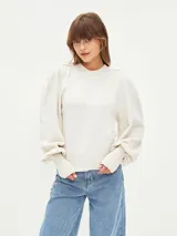 Buzo de tejido de punto color gris melange, con cuello redondo y mangas largas abullonadas con puños anchos acanalados.