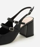 Zapato estilo Mary Jane de color negro, confeccionado en poliuretano con diseño cerrado y puntera cuadrada. Presenta tres tiras cruzadas en el empeine con hebillas metálicas ajustables, tira trasera con hebilla y taco bloque ancho.