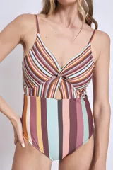 Traje de baño enterizo con estampado de rayas verticales y horizontales en tonos tierra, azul y rosado. Presenta escote en V con detalle anudado y abertura frontal.