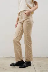 Pantalón de denim negro con diseño de tachas metálicas distribuidas en patrones curvos. Presenta un corte recto y tiro medio.