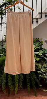 Pantalón pijama color beige, de corte ancho, con cintura elastizada, bolsillos traseros y detalles de hilo al tono.