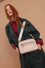 Bandolera de diseño moderno y funcional, confeccionada en nylon color marrón claro. Cuenta con múltiples compartimentos con cierre metálico, herrajes plateados y una correa ancha ajustable con detalle de marca.