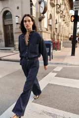 Camisa amplia de denim azul oscuro con cuello solapa, manga larga, bolsillo de plastrón en el pecho y cierre frontal con botones a presión dorados.