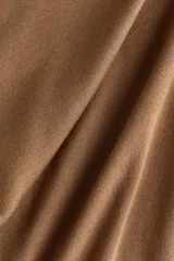 Buzo de punto fino suave color tostado, con diseño entallado, cuello alto acanalado, manga larga y remates acanalados en puños y bajo.