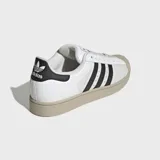 Championes Adidas Superstar II de diseño clásico con paneles divididos de cuero blanco y gamuza gris, con las icónicas tres tiras negras en el lateral, puntera de goma y suela en tono tostado.