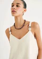 Vestido corto de corte recto y silueta holgada, con escote en V y breteles finos con detalle de argollas metálicas en los hombros.