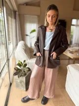 Blazer de cuero sintético marrón oscuro, de corte recto y holgado, con solapas clásicas, cierre frontal de botones y bolsillos frontales appliqués.