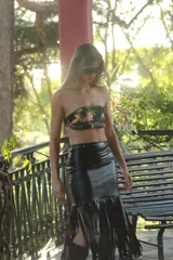 Falda midi negra de gabardina metalizada elastizada, con tachas en la cintura y flecos en el ruedo.
