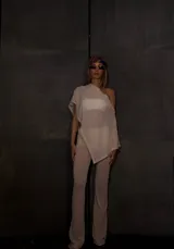 Poncho tejido color crema con cuello bote y corte asimétrico.