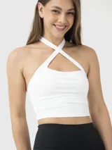 Top deportivo corto de color blanco con diseño de tirantes cruzados en el frente y escote tipo halter. Cuenta con sujetador integrado y almohadillas removibles.