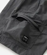 Bermuda cargo negra de tejido tecnológico (poliamida), con corte holgado, bolsillos laterales funcionales y cintura elástica con cordón ajustable.