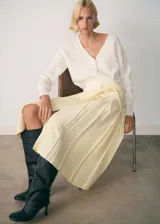 Cardigan de punto acanalado color blanco, con cuello en pico, manga larga y cierre frontal de botones. Presenta un diseño recto con una tira decorativa ajustable en la cintura con botones.