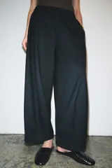 Pantalón de tiro medio con corte wide leg y cintura elástica ajustable. Presenta bolsillos laterales ocultos en las costuras y un diseño de pierna ancha con caída fluida.