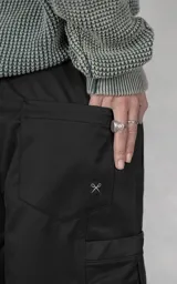 Pantalón de estilo utilitario oversize confeccionado en tejido técnico ripstop. Presenta cintura elástica con broche tipo mochilero, bolsillos cargo frontales de gran tamaño con cierre, bolsillos traseros tipo ojal y sistema de ajuste en los tobillos mediante broches a presión.