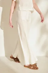 Pantalón negro de lino de tiro alto, con diseño ajustado en las caderas y perneras amplias y acampanadas con paneles insertados que generan mucho vuelo en el bajo.