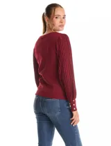 Buzo de tejido lurex marca Nanette, con cuello redondo y mangas largas con diseño plisado. Presenta puños ajustados con aplique de botones decorativos.