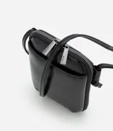 Cartera pequeña tipo porta celular de diseño compacto, confeccionada en poliuretano color negro. Cuenta con cierre de cremallera metálica, bolsillo frontal externo y correa fina ajustable para uso cruzado.