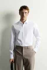 Camisa de corte slim fit, color celeste, con cuello italiano y manga larga con puños abotonados. Presenta un tejido con textura y cierre frontal de botones.