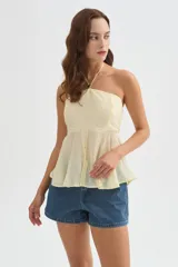 Top halter color amarillo claro, con escote strapless y detalle de argolla en el cuello, confeccionado en viscosa con diseño holgado y acabado fluido.
